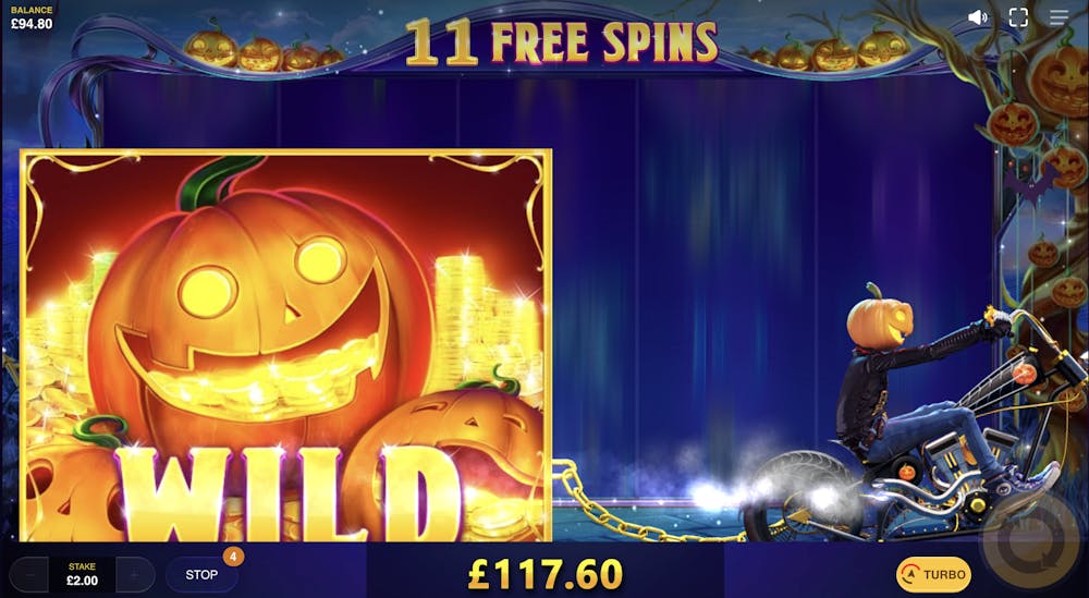 a pumpkin headed motorcyclist dragging a huge wild symbol, also a pumpkin, across the reels of the lucky halloween slot game